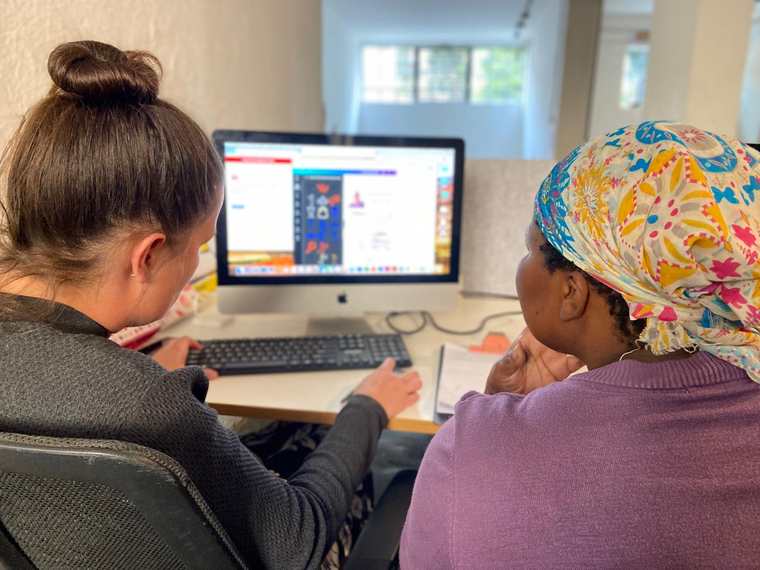 A mentor and a job club member sitting side by side at a computer, working through an online job application together.